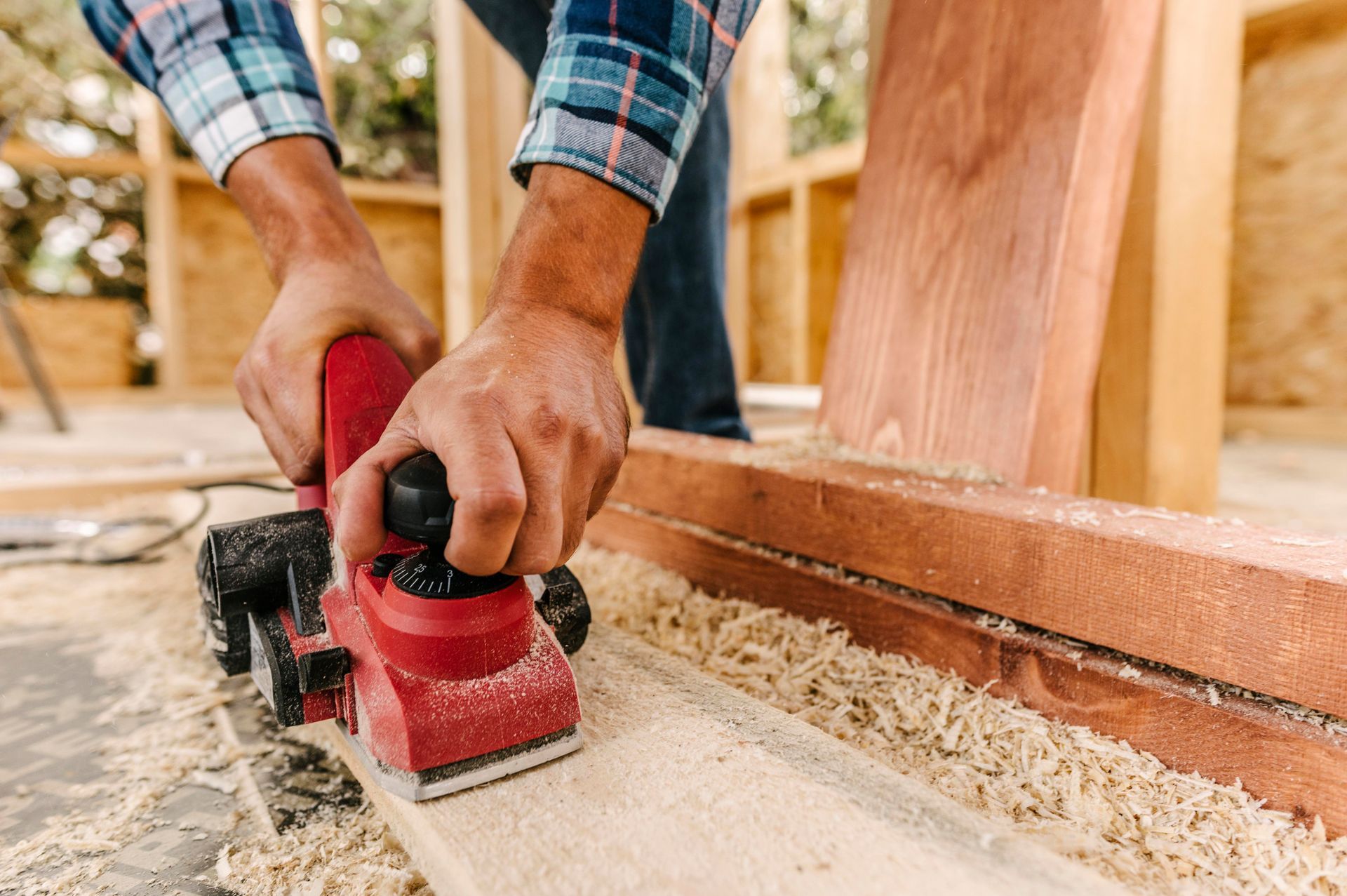 A man is sanding a piece of wood with an electric sander.