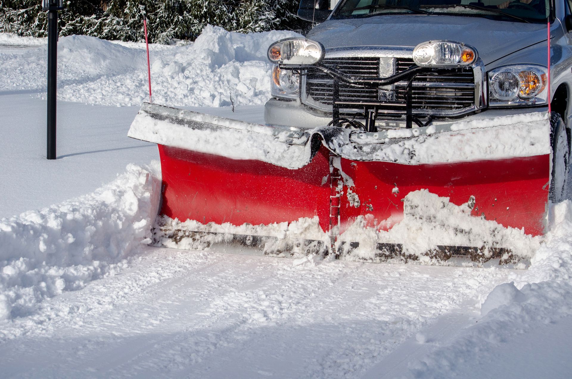 A snow plow is clearing snow from a driveway.