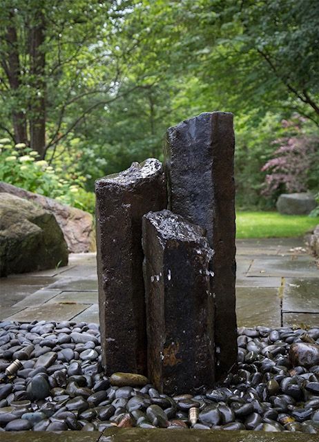 A fountain made of rocks and gravel in a garden.