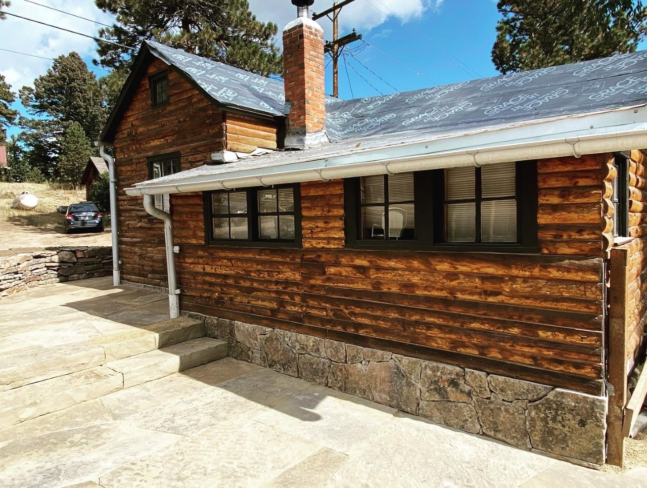 A log cabin with a car parked in front of it.