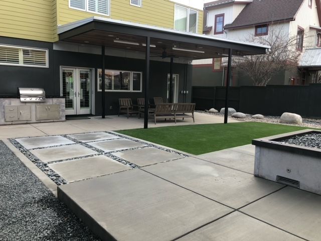 The backyard of a house with a covered patio and a grill