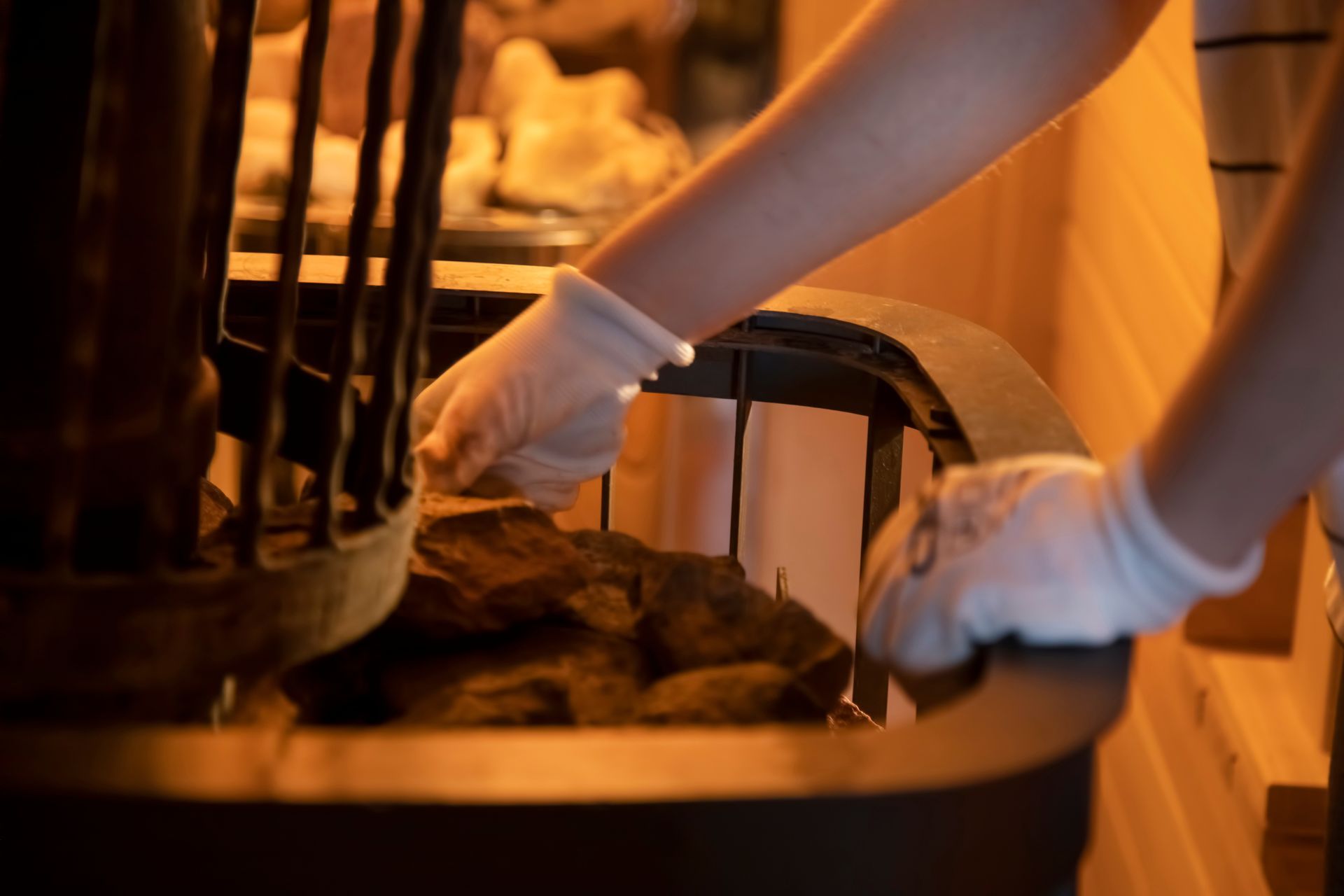 Gloved hands opening a warm oven, revealing a tray of food inside