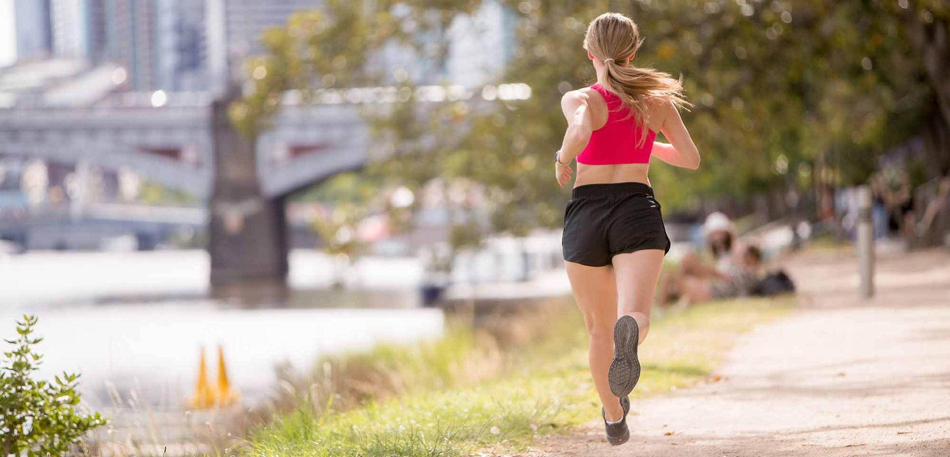 A woman is running on a path in melbourne next to yarra