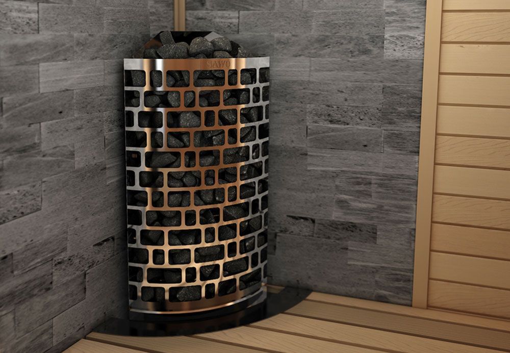 Curved black outdoor sauna heater with stones, set on a wooden floor against gray stone walls