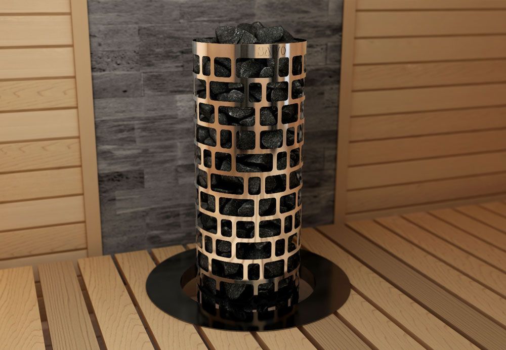 Tall black-and-copper sauna heater in a wooden room, with stone wall behind it.