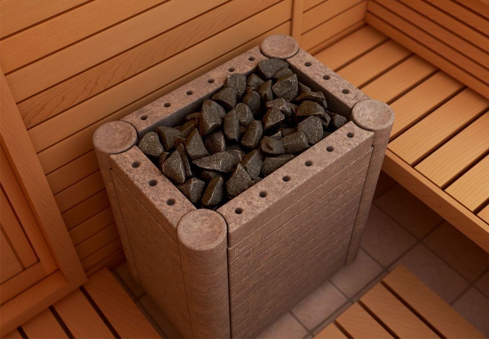 Wooden sauna heater filled with dark stones in a corner of a wood-paneled room