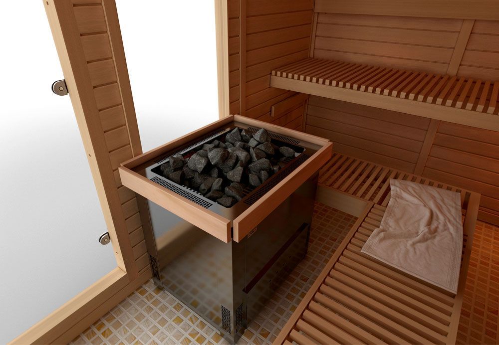 Wood-paneled sauna with a square stove filled with rocks and a wooden bench with a folded towel