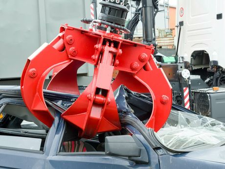 A blue car is being demolished by a red crane