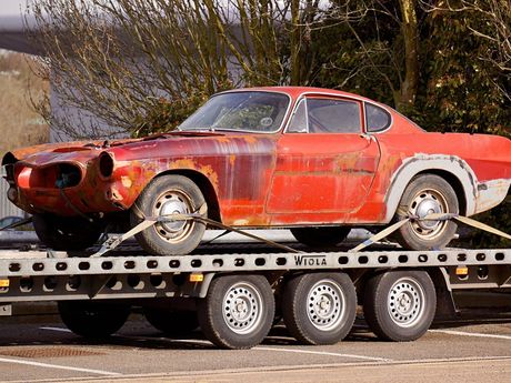 A red car is sitting on top of a trailer.