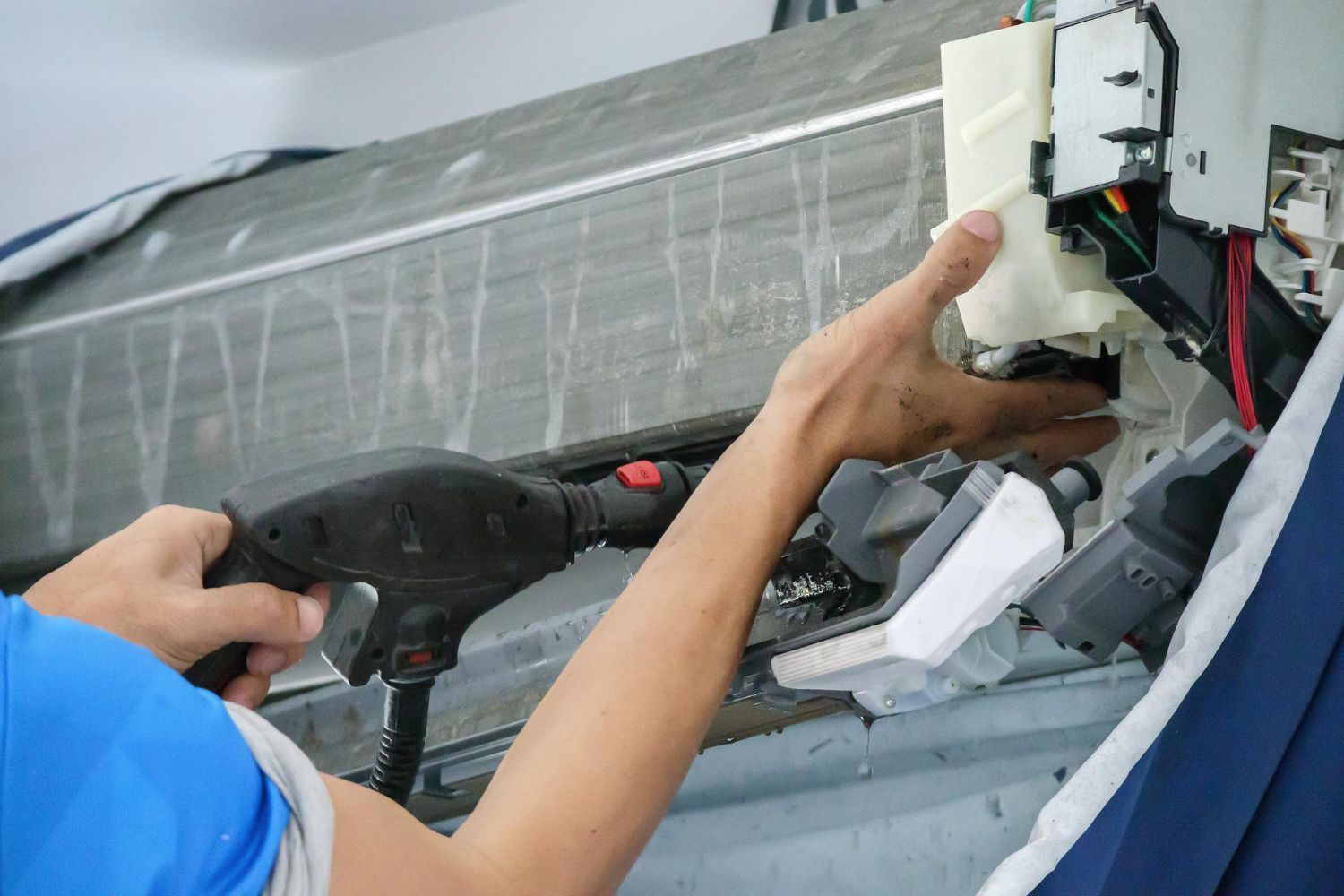 Technician adjusting wiring inside a wall-mounted air conditioner unit