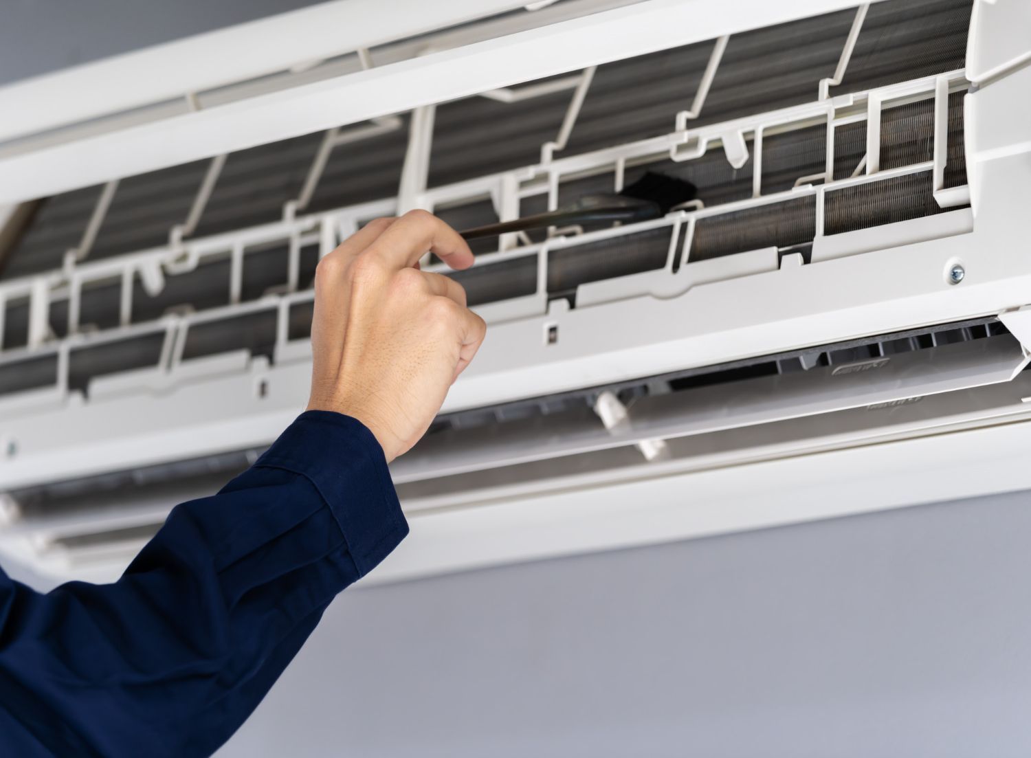 Hand adjusting the filter of a wall-mounted air conditioner unit