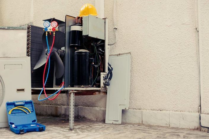 Electrical equipment and a blue toolbox on a concrete floor beside a wall, with wires and tubes attached