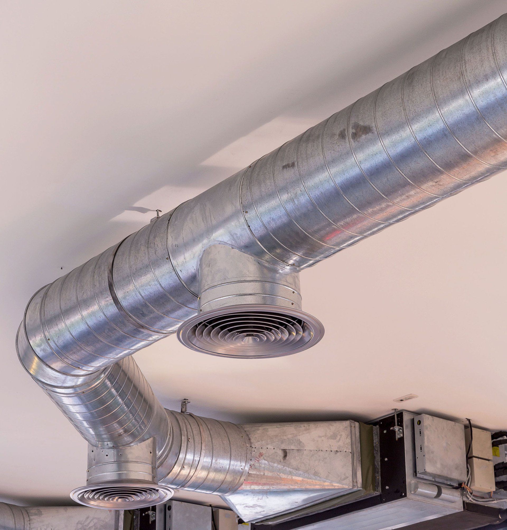 Outdoor HVAC units on a rooftop beside metal ductwork and a blue wall panel