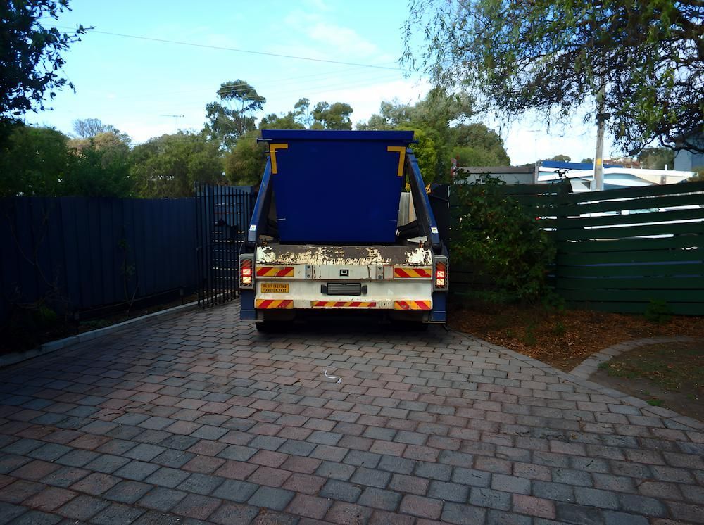 A Blue Dumpster is Parked on a Brick Driveway — Alexander Crane Tippers in Yass, NSW
