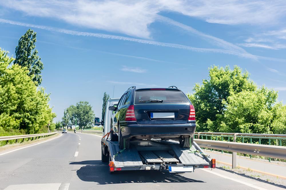 A Car is Being Towed Down a Highway by a Tow Truck — Alexander Crane Tippers in Yass, NSW