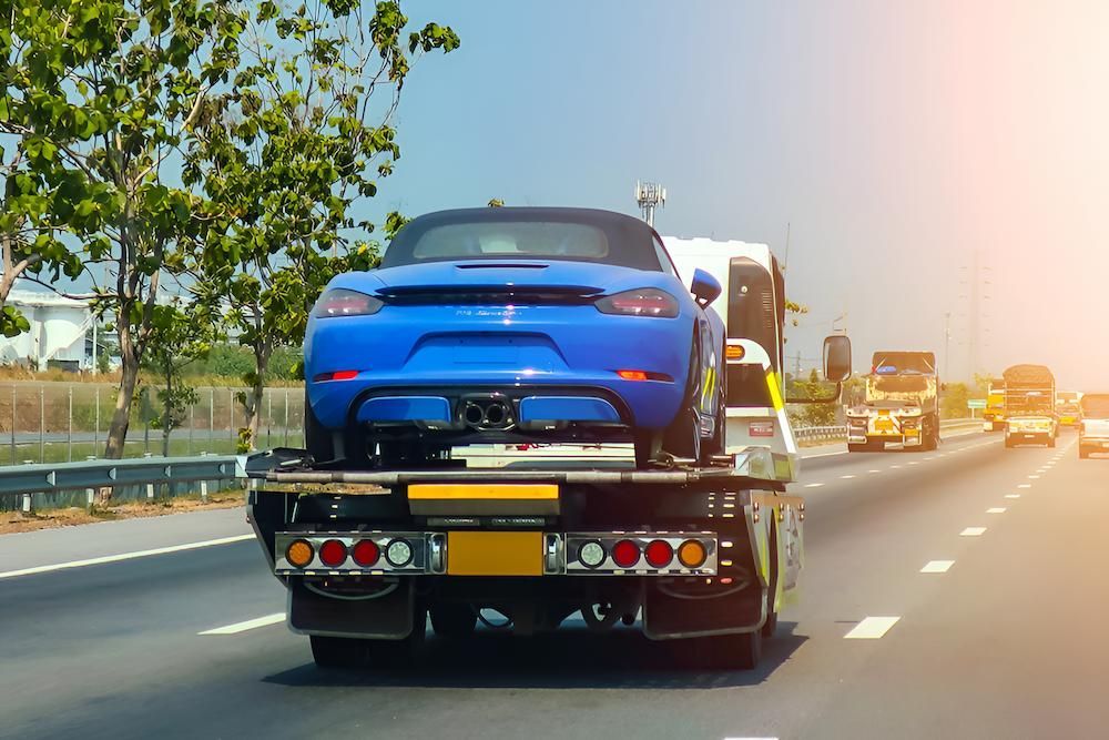 A Blue Car is Being Towed Down a Highway by a Tow Truck — Alexander Crane Tippers in Goulburn, NSW