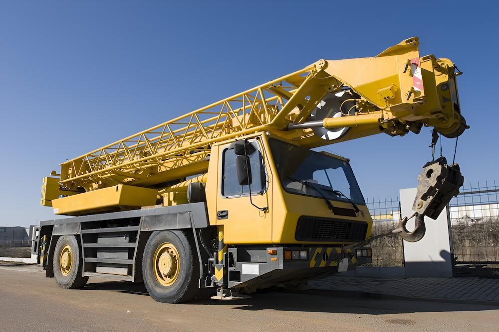 A Yellow Truck With a Crane Attached to It is Parked in a Parking Lot — Alexander Crane Tippers in Yass, NSW