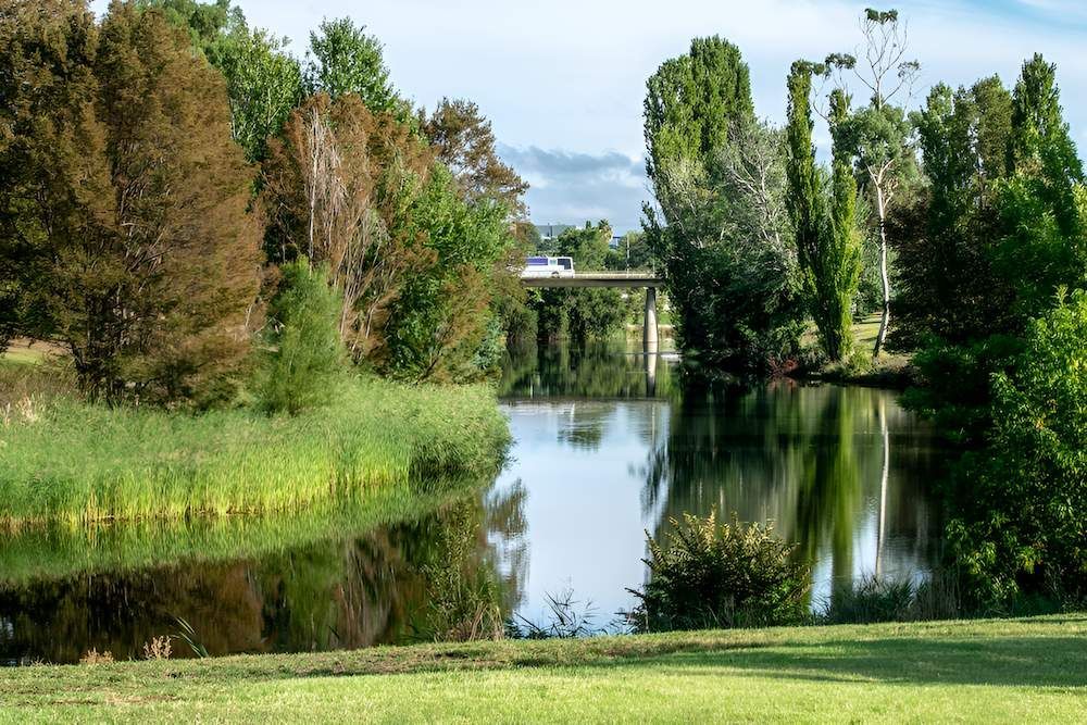 A River Surrounded by Trees and Grass With a Bridge — Alexander Crane Tippers in Bungendore, NSW