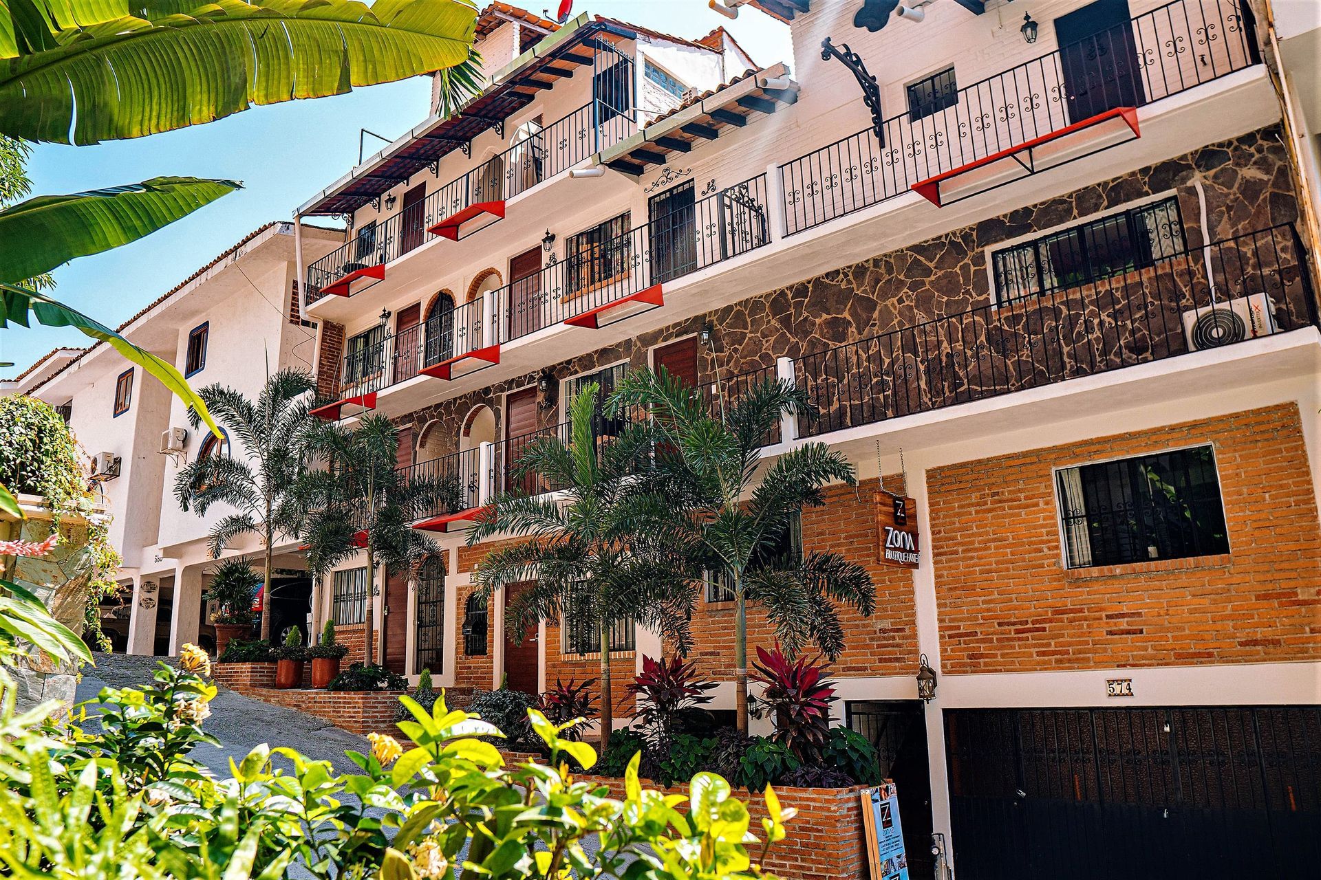 A large building with a lot of windows and balconies is surrounded by trees and bushes.