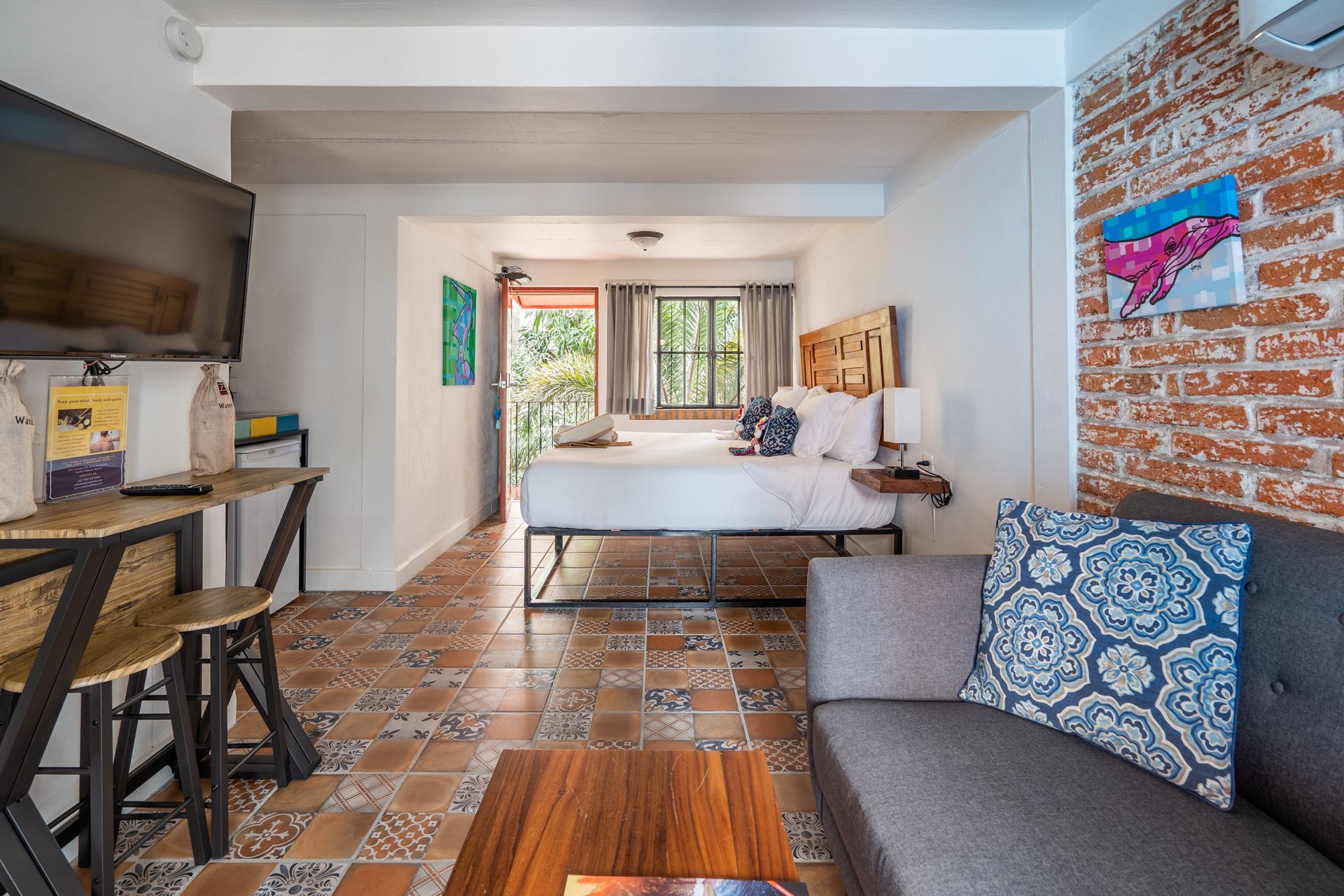 Small studio apartment with bed, couch, and brick accent wall.