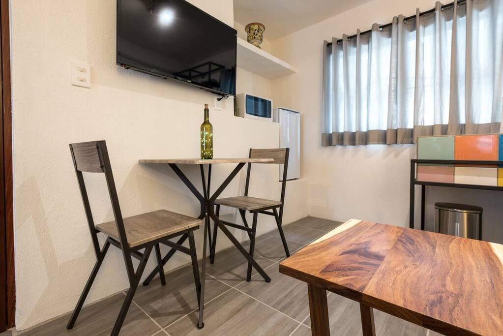 A living room with a table and chairs and a flat screen tv.