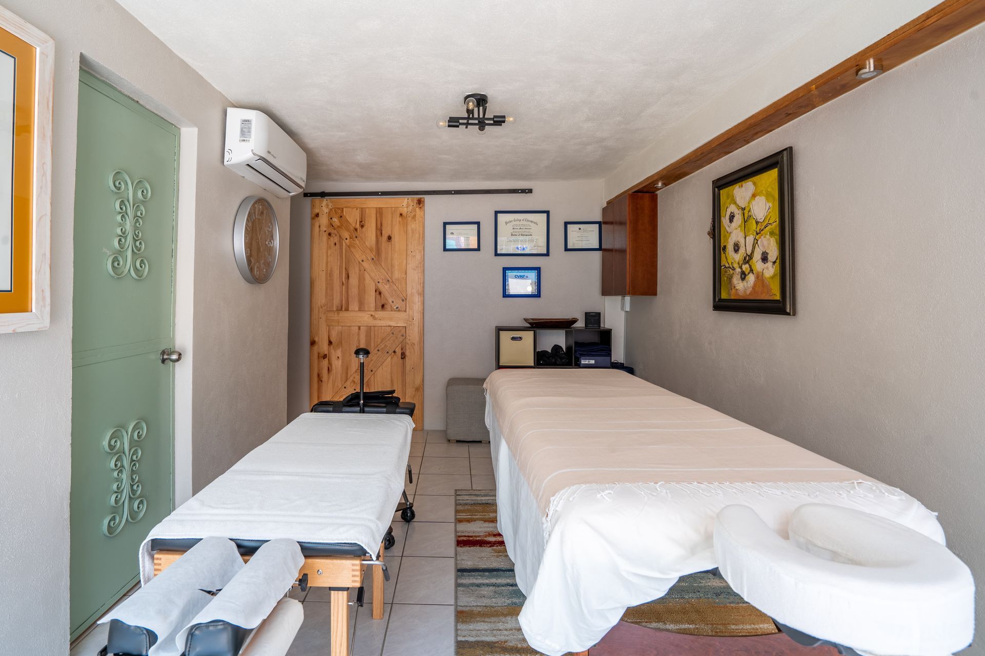 A room with two massage tables and a clock on the wall.