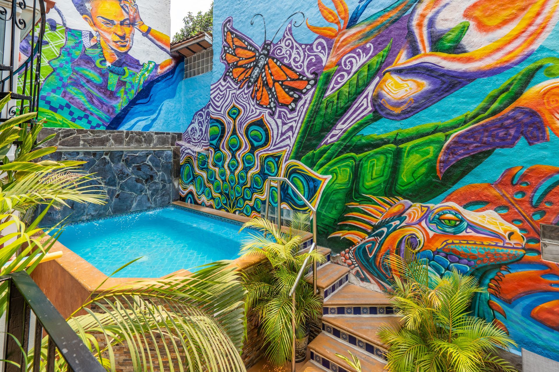 Colorful mural with a pool, featuring a person, butterfly, lizard, and tropical plants.