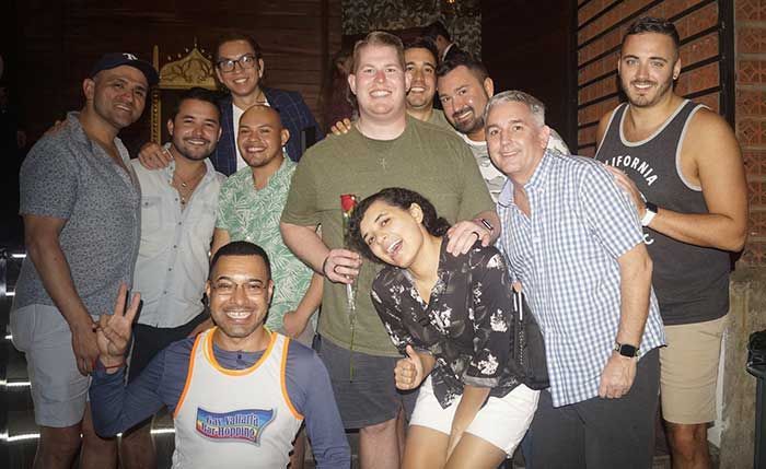 A group of ten people smile together for a photo, with one person in the front giving a peace sign.