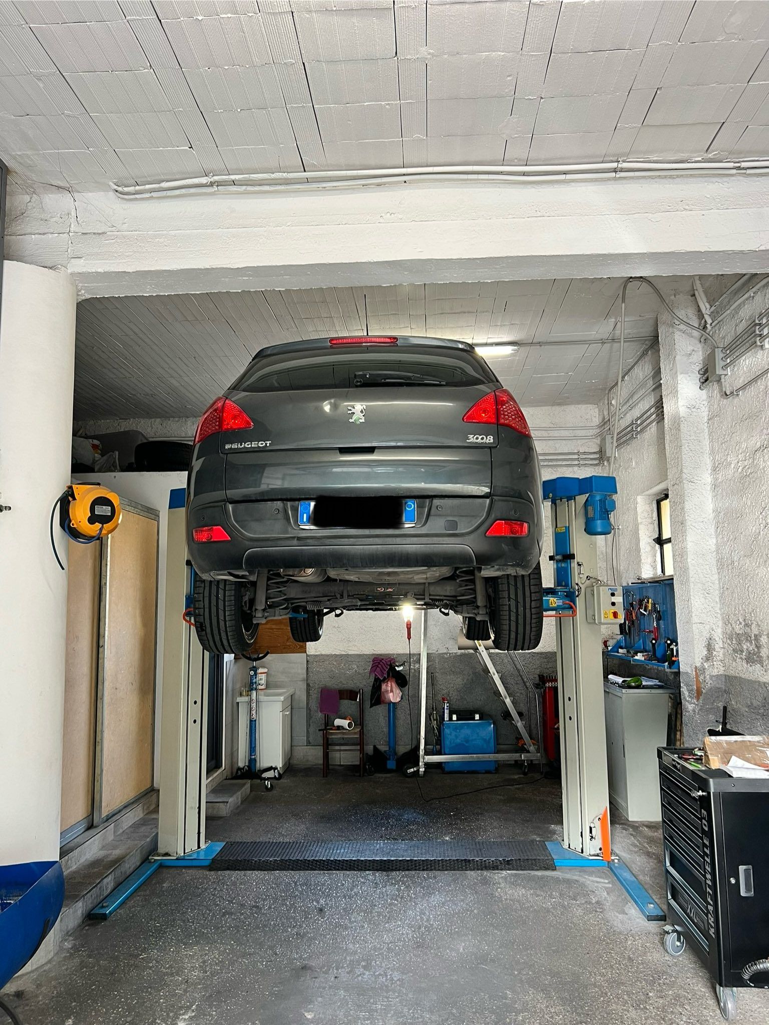 Un'auto grigia sollevata su un ponte sollevatore