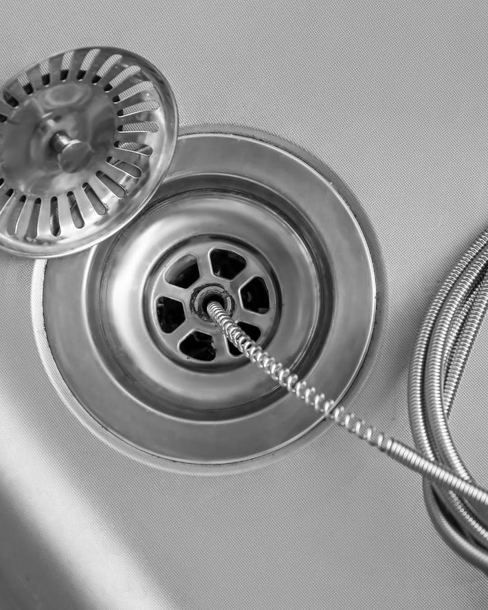 Kitchen sink drain with a strainer and a flexible metal drain snake inserted into the drain
