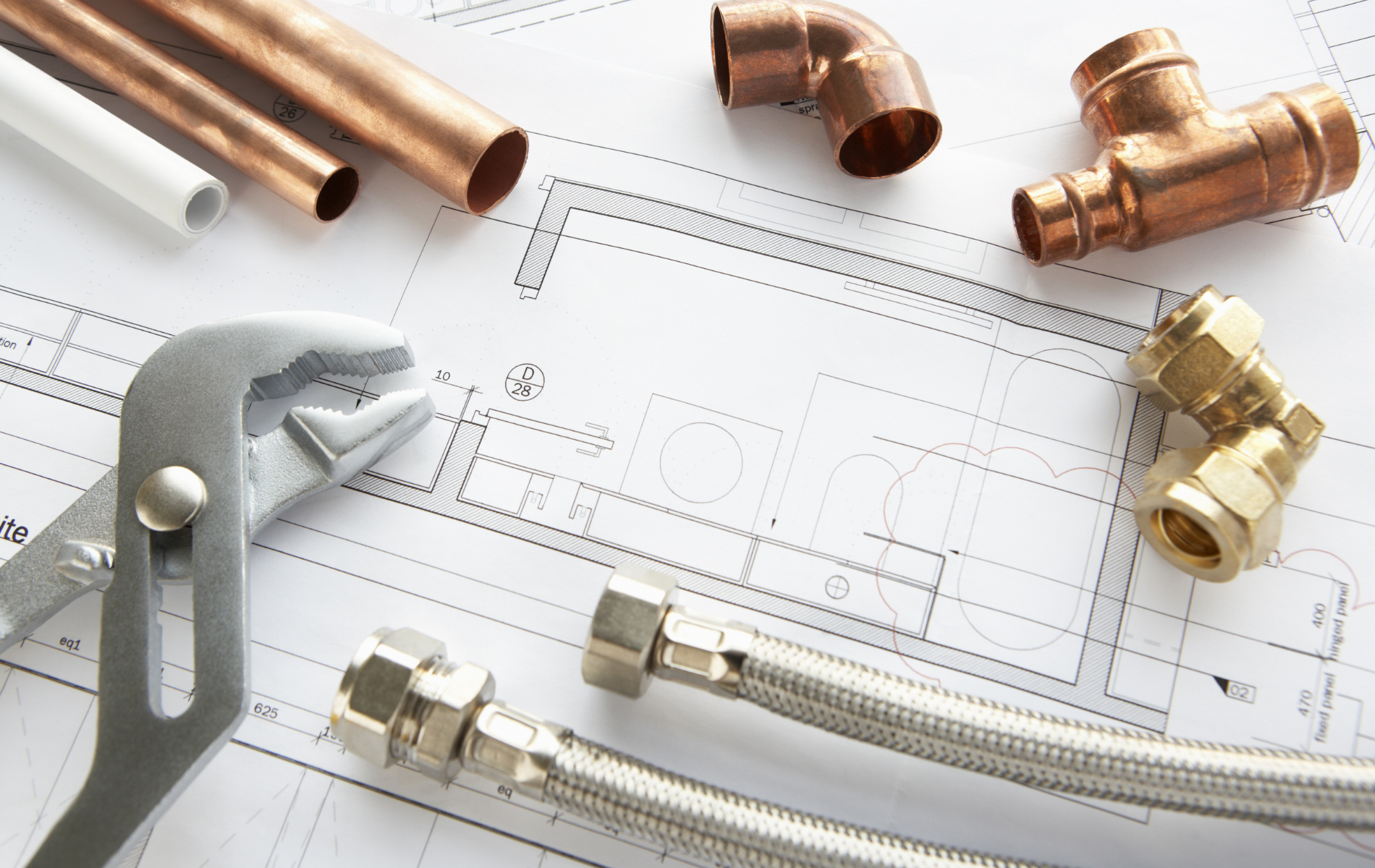 Plumbing tools and pipe fittings on a blueprint plan