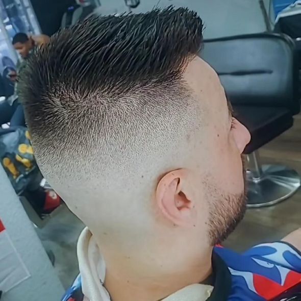 Close-up of a man with a faded haircut in a barber chair, seen from the side.
