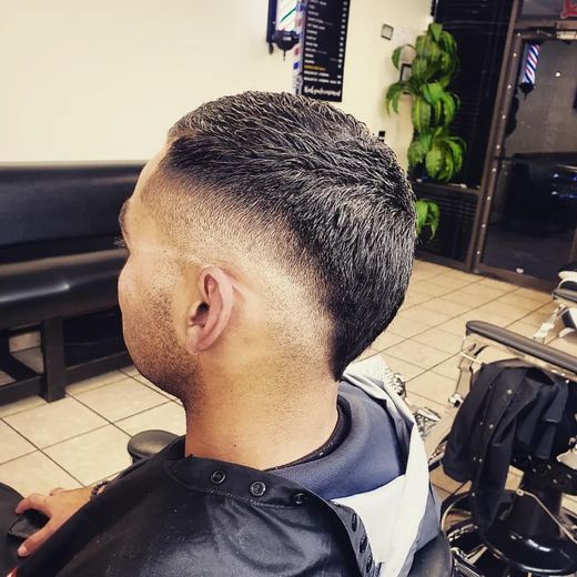 Close-up of a fresh tapered haircut in a barber shop, showing a textured top and faded sides