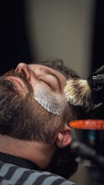 Shaving cream brushed onto a man’s face during a close-up barber shave
