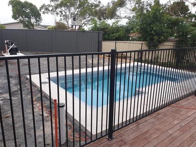 Black Fenced Small Pool Surrounded by Concrete and Wood Decking — Clearwater Pools Hallidays Point in Gloucester, NSW