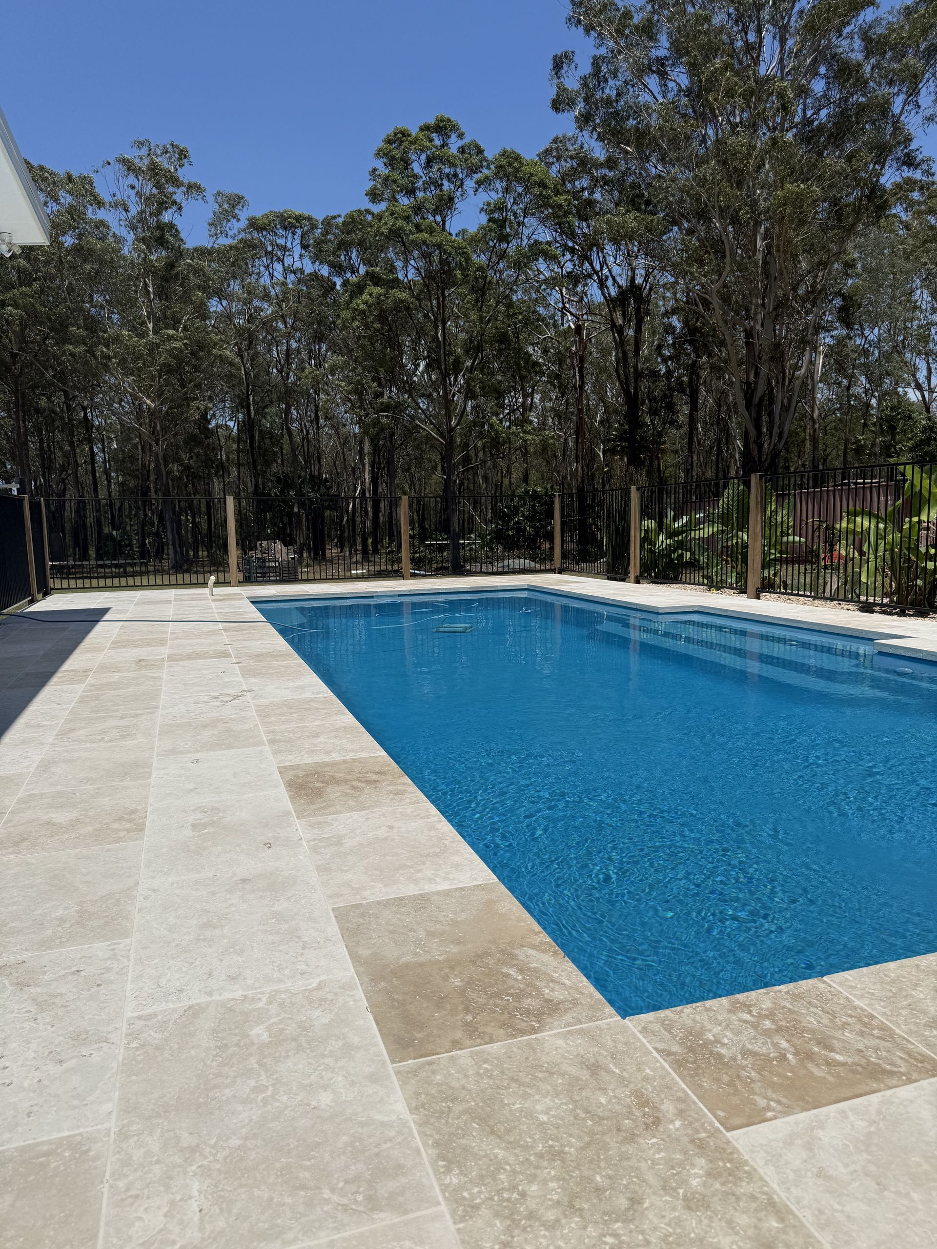 Pool Surrounded by Light Stone Tiles, and a Forest — Clearwater Pools Hallidays Point in Hallidays Point, NSW