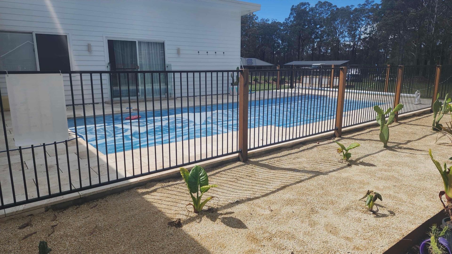 Pool Surrounded by a Fence and Plants; a House — Clearwater Pools Hallidays Point in Hallidays Point, NSW