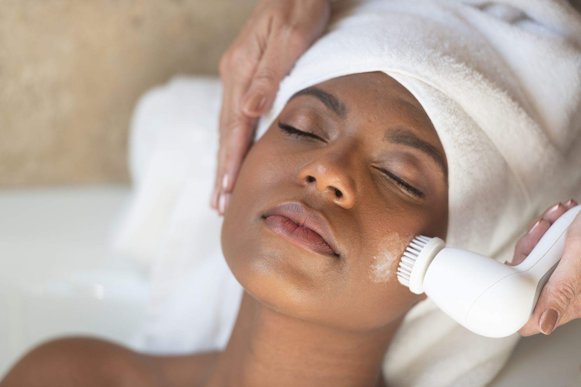 A woman with a towel wrapped around her head is getting a facial treatment.