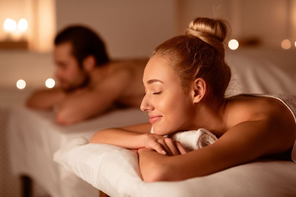 A man and a woman are laying on massage tables in a spa.