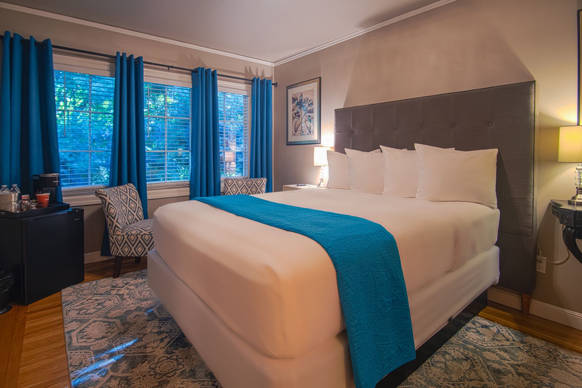A hotel room with a king size bed and blue curtains.