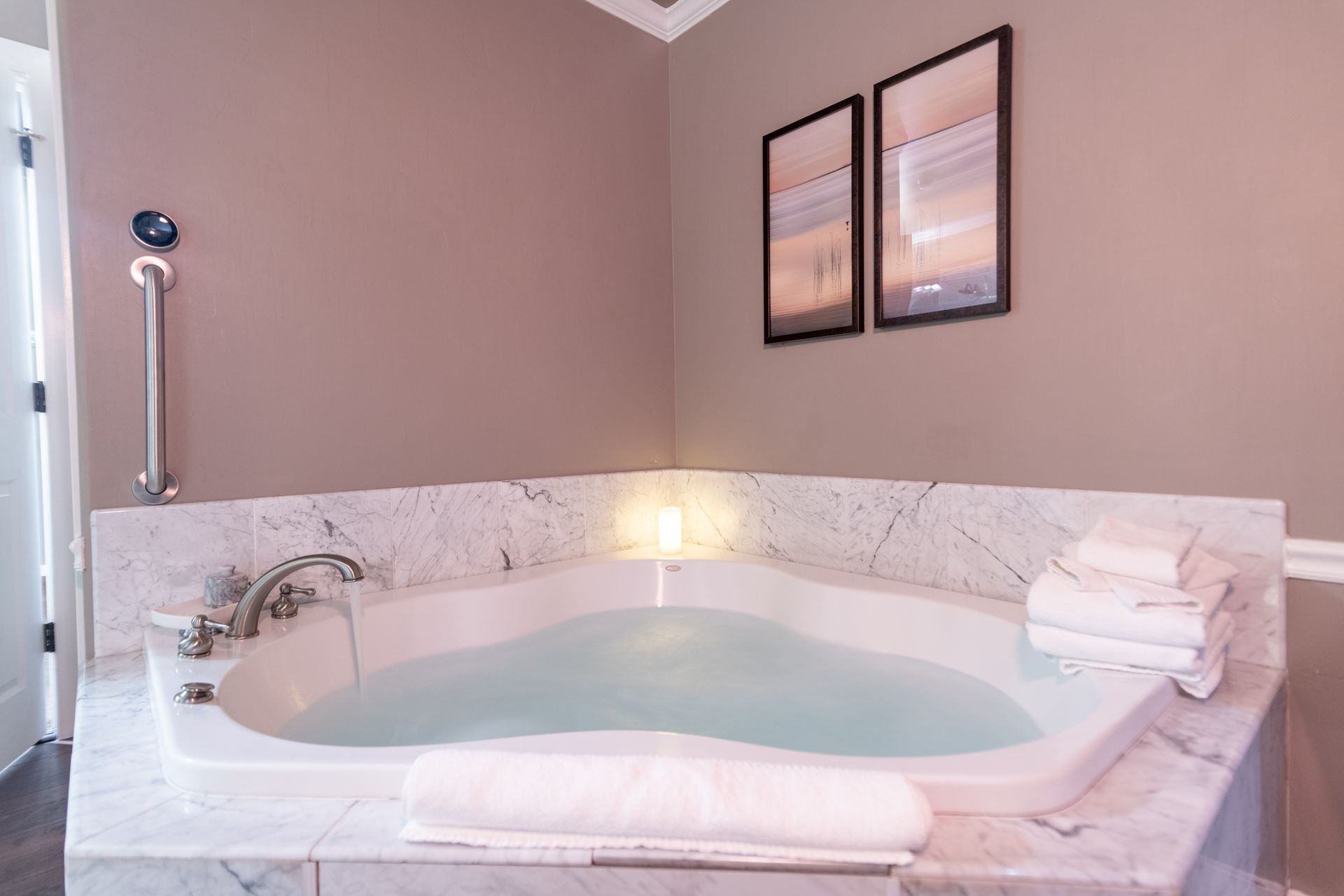 A bathroom with a jacuzzi tub and two pictures on the wall.