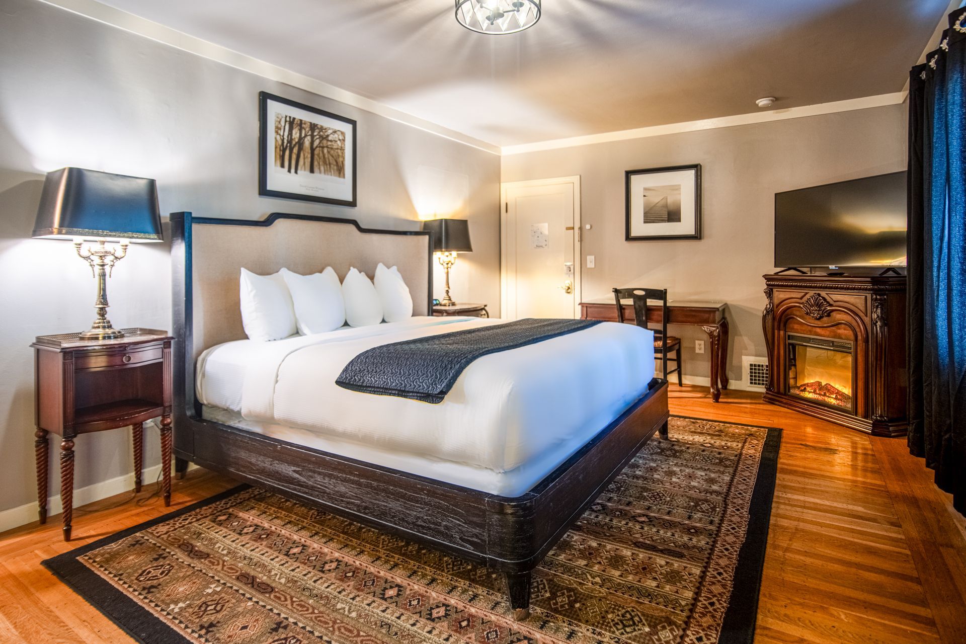 A hotel room with a king size bed and a fireplace.