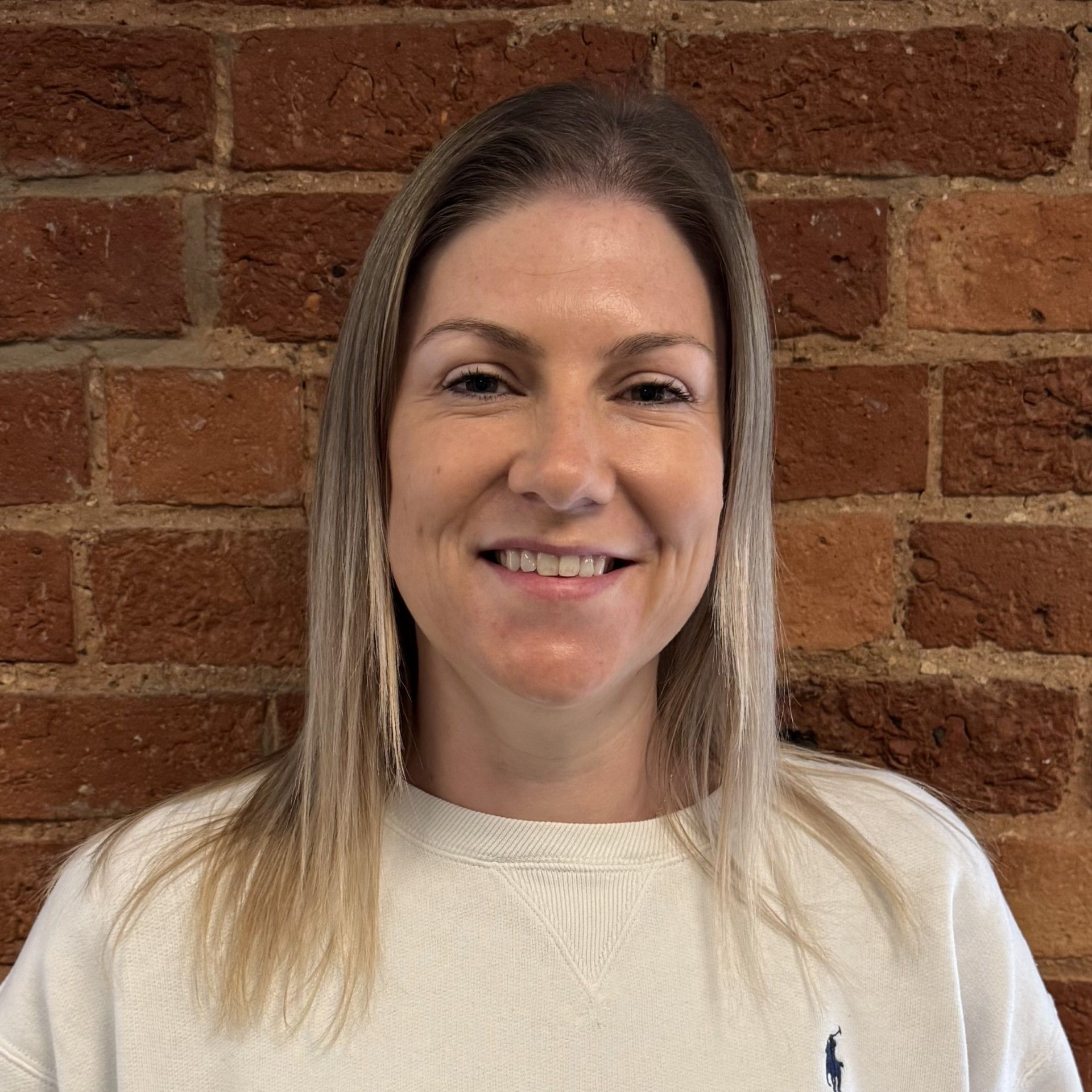 A woman wearing a black sweatshirt is smiling for the camera.