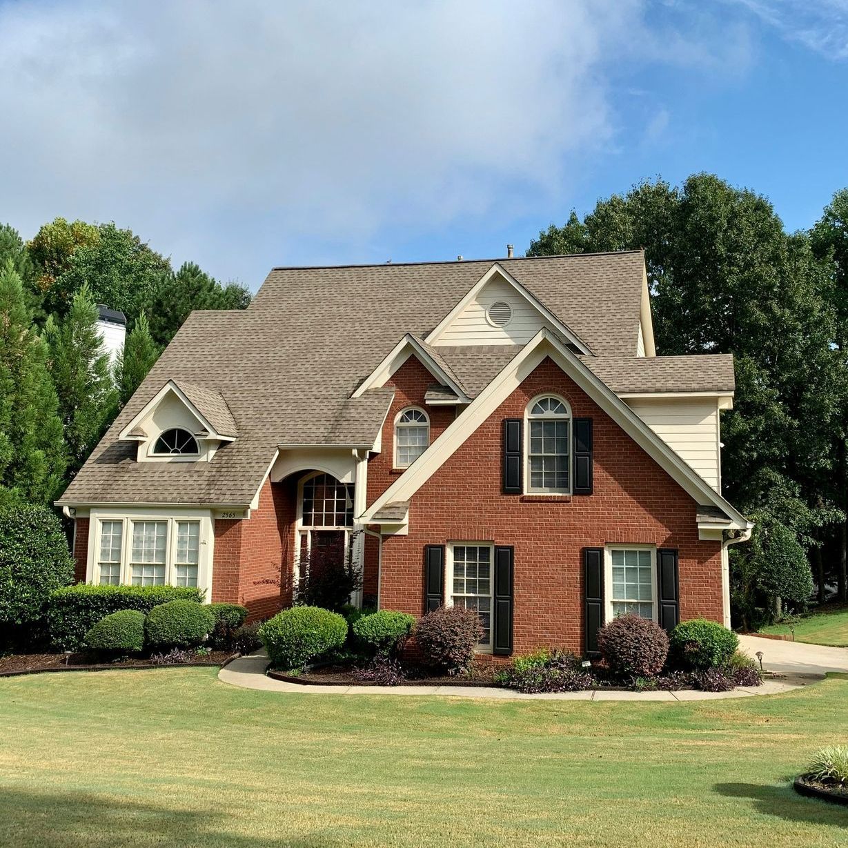 A large brick house with a brown roof and black shutters
