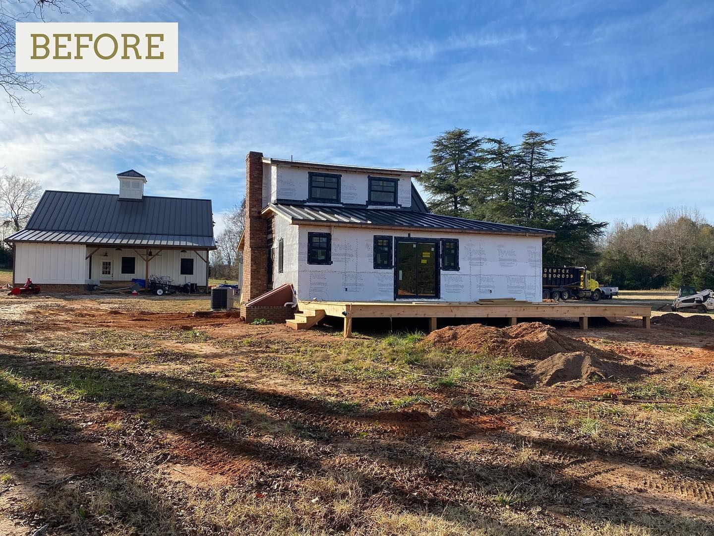 Construction site: unfinished house with a brick chimney and a detached building, set in a field.