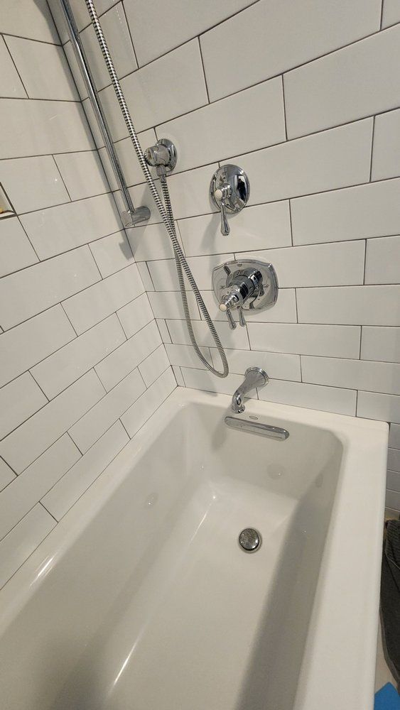 White bathtub with chrome shower fixtures against white subway tile.