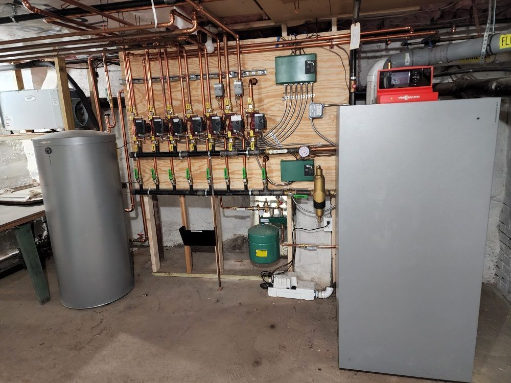 Basement with heating system components, including boiler, water tank, and pipes.