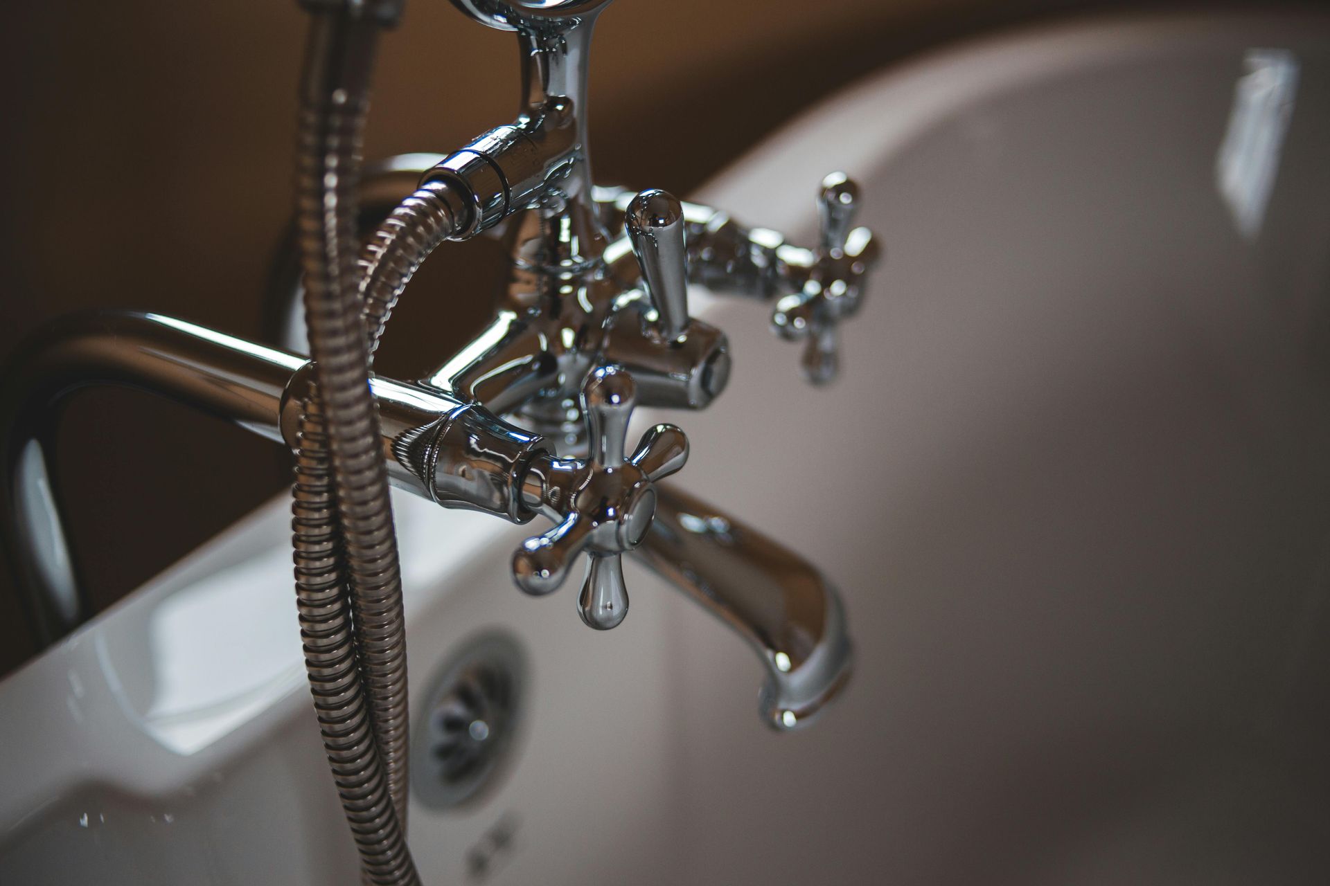 Chrome bathtub fixtures, including a faucet and showerhead, against a white tub.