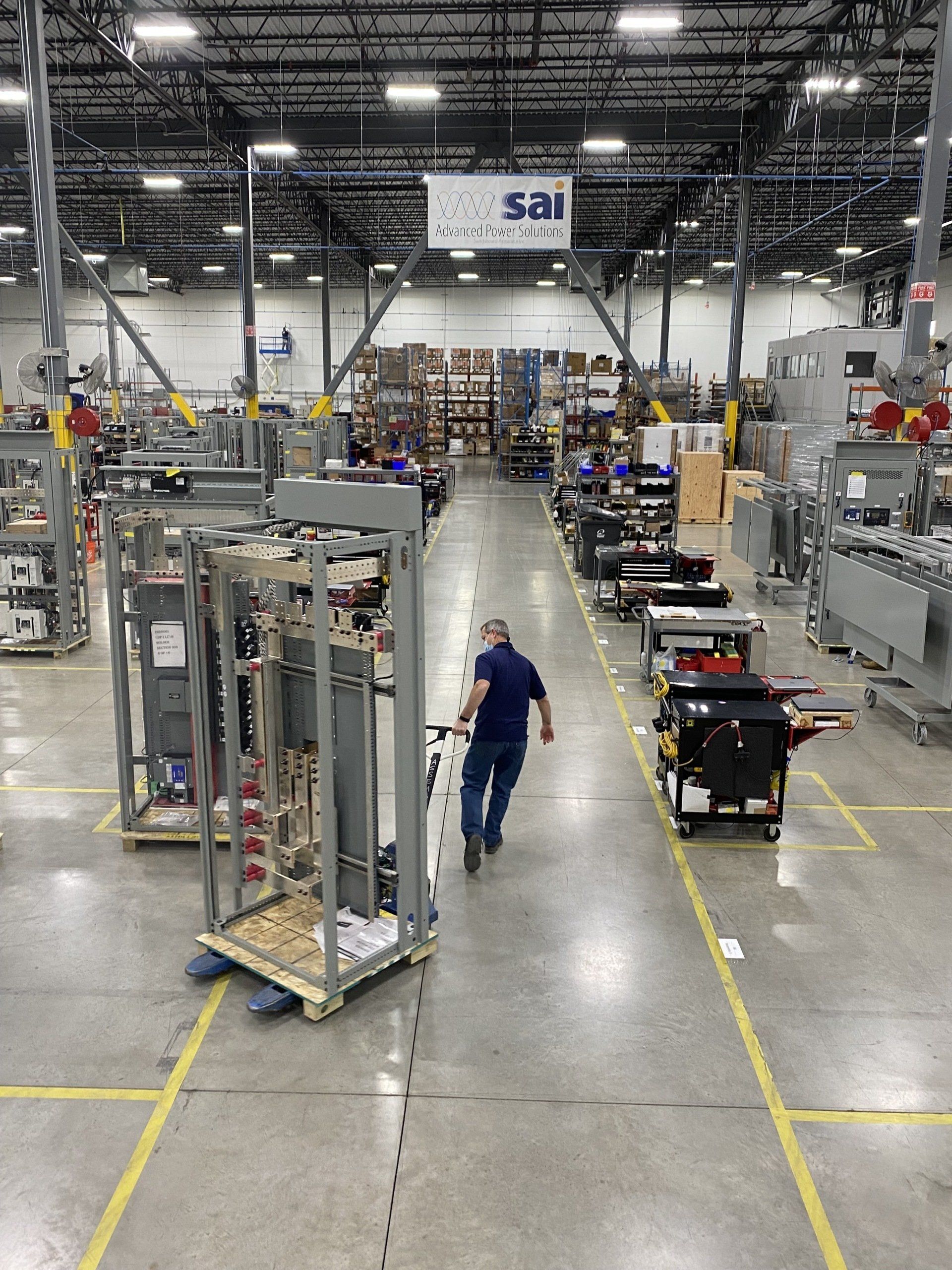 A man is walking through a warehouse with a sign that says sai