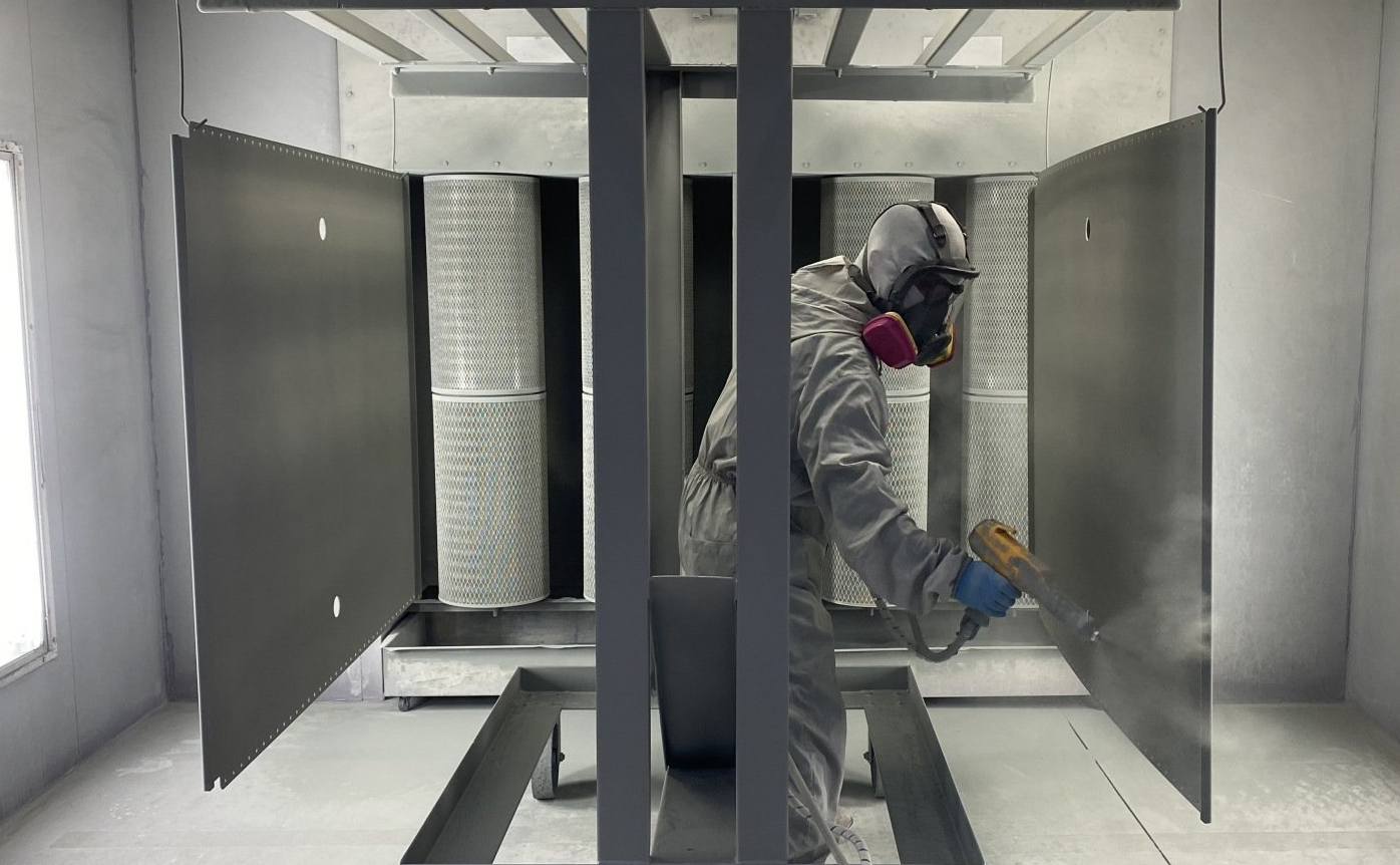 A man in a protective suit is spray painting a wall in a room.